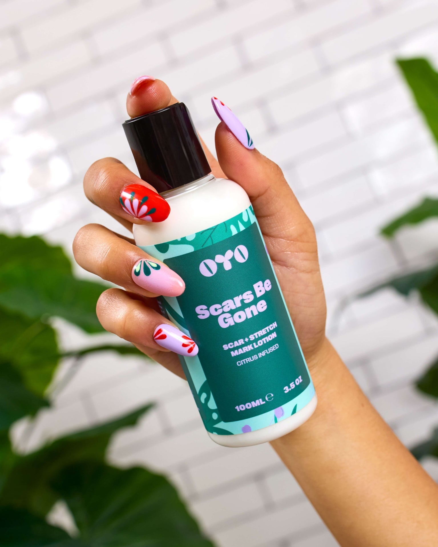 Hand holding Scars Be Gone lotion, a natural skincare solution for scars and stretch marks, brightening and soothing skin.