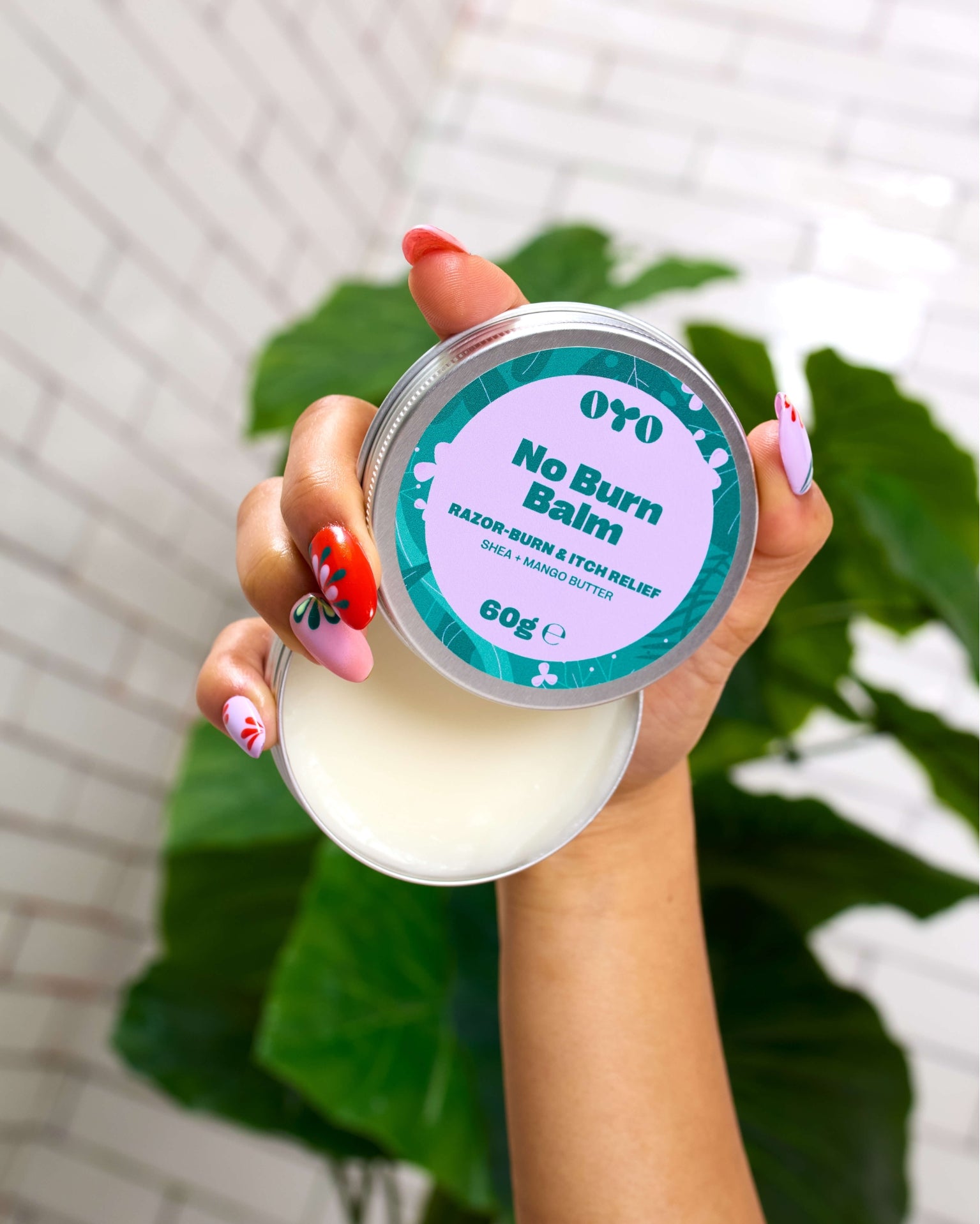 Hand holding No Burn Balm with shea and mango butter for soothing post-shave irritation.