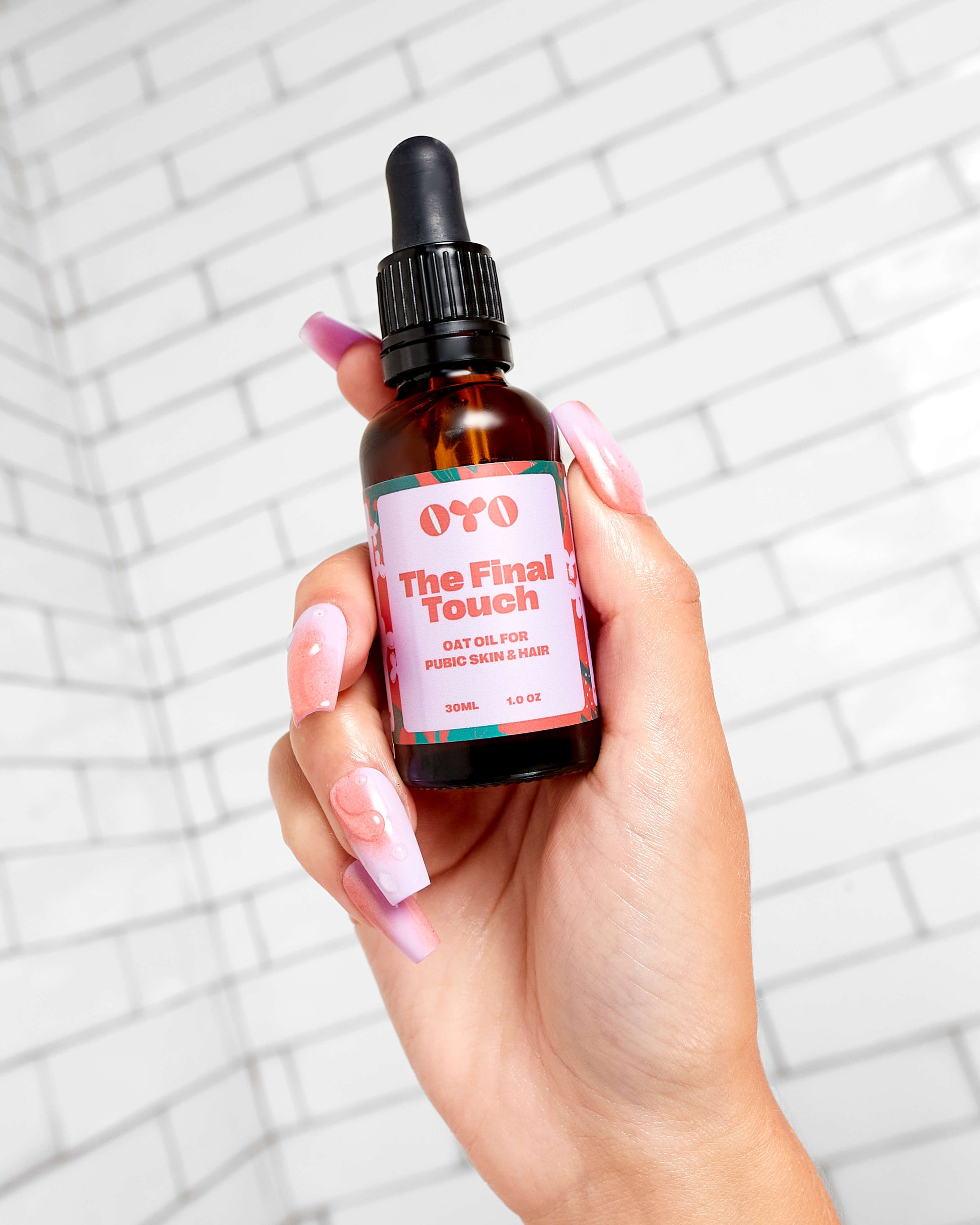 The Final Touch oat oil for perfect skin & hair, held in a hand with stylish nails, against a clean tile background.